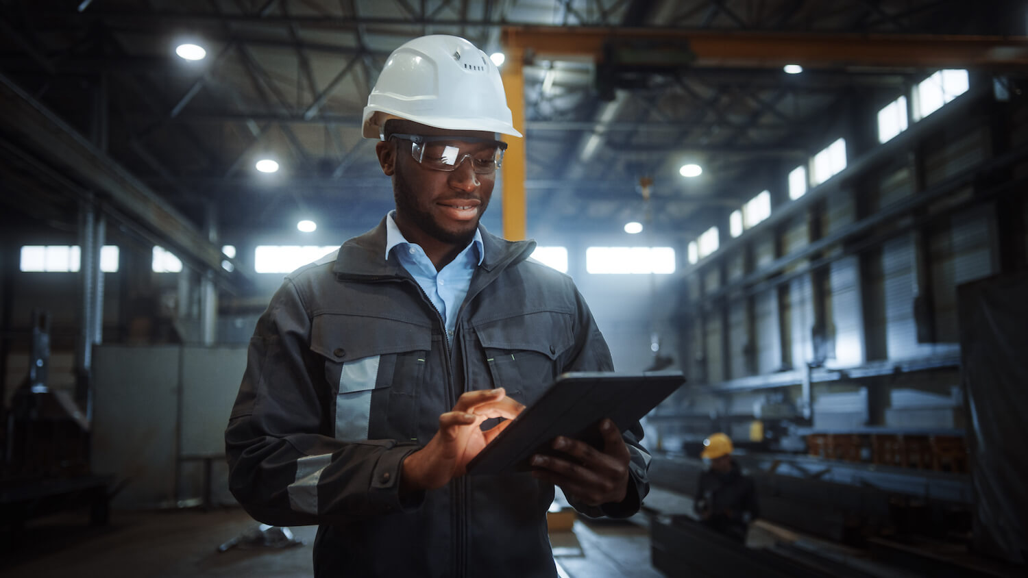 Professional Heavy Industry Engineer Worker Wearing Safety Uniform and Hard Hat Uses Tablet Computer